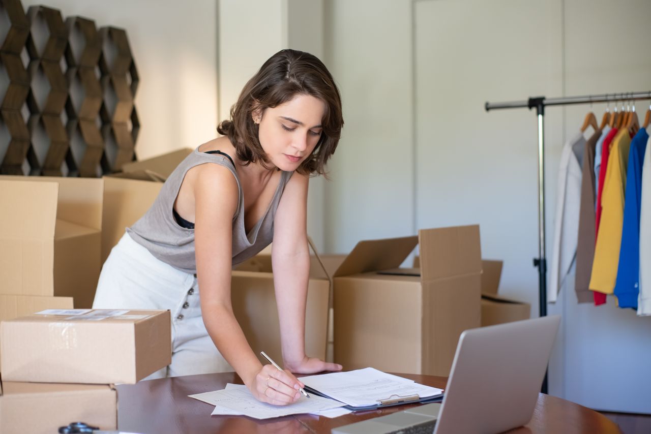 Store owner managing online orders with parcels and a laptop